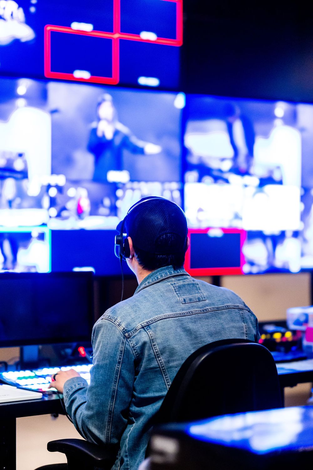 Realizador operando un switcher frente a un muro de monitores multicámara